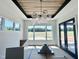 Dining area featuring a modern chandelier, large windows with scenic view, and dark framed glass doors at 280 Forest Bridge Rd, Franklinton, NC 27525