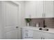Functional laundry room featuring white cabinets, a stylish backsplash, and a sink with modern fixtures at 33 Macy Cir, Wendell, NC 27591