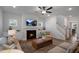Cozy living room featuring a fireplace, mounted TV, ceiling fan, and neutral decor with access to the staircase at 33 Macy Cir, Wendell, NC 27591