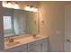 Bathroom with double sinks, white cabinets, large mirror, and neutral paint color at 73 High Hampton Way, Fuquay Varina, NC 27526