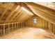Unfinished attic space with exposed wood, a window and a single light fixture at 1414 Whippoorwill Ln, Chapel Hill, NC 27517