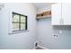Bright laundry room featuring white cabinets, a shelf with baskets, a window and neutral paint at 1414 Whippoorwill Ln, Chapel Hill, NC 27517