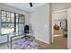 Bright home office with a large window, glass desk, ceiling fan, and an open doorway to the living area at 1414 Whippoorwill Ln, Chapel Hill, NC 27517