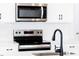 Close-up of a stainless steel stove and microwave with white cabinets and a modern black kitchen faucet at 70 Little Creek Dr, Lillington, NC 27546