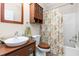 Bright bathroom features a wood vanity, a vessel sink, and a decorative shower curtain at 413 Chadwick Ln, Efland, NC 27243