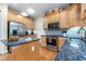 Spacious kitchen with stainless appliances, wood cabinets, granite countertops, an eat-in island, and hardwood flooring at 413 Chadwick Ln, Efland, NC 27243