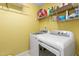 Bright laundry room with washer, dryer, shelves and yellow walls at 413 Chadwick Ln, Efland, NC 27243