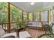 Relaxing screened porch with wooden floors, wicker furniture, ceiling fan, and wooded views at 413 Chadwick Ln, Efland, NC 27243
