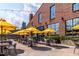 Outdoor patio with seating, featuring yellow umbrellas and a view of the brick building and city skyline at 10 Seawell Ave # 102, Raleigh, NC 27601
