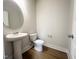 Clean, neutral half bathroom featuring a pedestal sink, modern toilet, and hardwood floors at 240 Fast Pitch Ln, Four Oaks, NC 27524