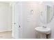 Bright half bath featuring a pedestal sink, round mirror, and neutral paint at 240 Fast Pitch Ln, Four Oaks, NC 27524