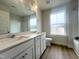 Bright bathroom with double sinks, white cabinets, hardwood floors, and a large window at 240 Fast Pitch Ln, Four Oaks, NC 27524