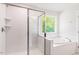Modern bathroom with a glass-enclosed shower and soaking tub by the window at 240 Fast Pitch Ln, Four Oaks, NC 27524