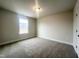 Bedroom features neutral carpet, white trim, and a bright window at 240 Fast Pitch Ln, Four Oaks, NC 27524