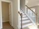 Bright foyer featuring stairs with wood and white banisters, hardwood floors, and a doorway at 240 Fast Pitch Ln, Four Oaks, NC 27524