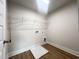 Spacious laundry room with hardwood floors, utility connections, a drop-in sink basin and overhead wire shelving at 240 Fast Pitch Ln, Four Oaks, NC 27524