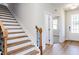 Inviting entryway featuring wood stairs, wood floors, and a glimpse into a bright, carpeted room at 266 Fast Pitch Ln, Four Oaks, NC 27524