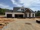 New construction home featuring a three-car garage, stone accents, and a covered entryway at 52 Macy Cir, Wendell, NC 27591