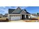 A charming new home with a brick facade, gray siding, and a well-manicured lawn under a partly cloudy sky at 1044 Fairhaven Dr # 100, Mebane, NC 27302