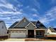 A charming new home with a brick facade, gray siding, and a well-manicured lawn under a partly cloudy sky at 1044 Fairhaven Dr # 100, Mebane, NC 27302