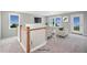 Bright, carpeted loft area with white railing, seating, and natural light from the surrounding windows at 34 Macy Cir, Wendell, NC 27591