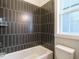 Modern bathroom with a dark tiled shower, white fixtures, and a window for natural light at 100 Mossy Falls Way, Wendell, NC 27591