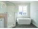 Modern bathroom featuring a soaking tub, glass shower and beautiful window light at 100 Mossy Falls Way, Wendell, NC 27591