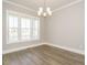 Bright dining room showcasing a modern chandelier, large windows, and beautiful flooring at 100 Mossy Falls Way, Wendell, NC 27591