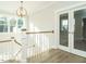 Bright hallway with wood floors, white railing, modern lighting, and glass doors at 100 Mossy Falls Way, Wendell, NC 27591