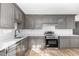 This kitchen features stainless steel appliances, gray cabinets, light countertops, and hardwood floors at 234 Crumpler Rd, Kenly, NC 27542