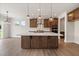 A spacious kitchen featuring a large island, stainless steel appliances, dark wood cabinets, and hardwood style flooring at 1224 Cricket St, Elon, NC 27244
