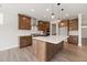 An inviting kitchen boasts a center island, stainless appliances, and dark cabinets, with stylish lighting and hardwood flooring at 1224 Cricket St, Elon, NC 27244