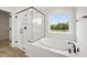 Modern bathroom with glass enclosed shower, soaking tub, large window, and attractive hardware at 1228 Cricket St, Elon, NC 27244