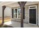 Inviting front porch with stone accents, timber supports, and a stylish black front door at 1228 Cricket St, Elon, NC 27244