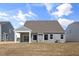 Rear view of the house with a covered patio, grassy yard, and neutral-colored siding at 1232 Cricket St, Elon, NC 27244