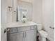 Bathroom with gray cabinets, a mirror, and a toilet. Natural light from the window at 1232 Cricket St, Elon, NC 27244