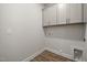 Functional laundry room with gray cabinets, light walls, and hardwood floors at 1232 Cricket St, Elon, NC 27244