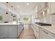 Bright, open kitchen boasts a large island, modern white cabinets, stainless hood, and hardwood floors at 1301 Cricket St, Elon, NC 27244