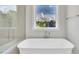 Soaking tub and glass shower overlooking a window showcasing a serene backyard view at 27 Asti Ct, Clayton, NC 27527