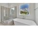 Spa-like bathroom features a freestanding tub and glass-enclosed shower with backyard views at 27 Asti Ct, Clayton, NC 27527