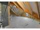 Unfinished attic space with exposed wooden beams and a small window offering natural light at 5124 Grist Stone Way, Youngsville, NC 27596