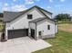 A three car garage with modern doors and black trim on a home with light colored siding and newly installed lawn at 5124 Grist Stone Way, Youngsville, NC 27596