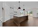 Bright kitchen showcasing a central island with pendant lights, white cabinetry, and dark hardwood floors at 5124 Grist Stone Way, Youngsville, NC 27596