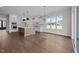 Open-concept kitchen with white cabinets, a central island, stainless steel appliances, and hardwood floors at 5124 Grist Stone Way, Youngsville, NC 27596