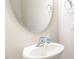 Close-up of a clean, white bathroom sink with a modern faucet and oval mirror at 1024 Jarrett Bay Rd, Willow Springs, NC 27592