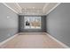 Bright dining room featuring gray walls, hardwood floors, a modern chandelier, and a large window offering natural light at 418 S Cross St, Youngsville, NC 27596