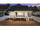 View of the rear exterior of the home at dusk, showcasing a covered porch with stairs and an open backyard space at 418 S Cross St, Youngsville, NC 27596