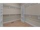Walk-in closet featuring custom shelving and ample storage space, and wood floors at 418 S Cross St, Youngsville, NC 27596