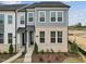 A close-up of a gray and white modern townhome exterior with brick accents and manicured landscaping at 810 Barlow Dr, Knightdale, NC 27545