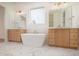 Bright and spacious bathroom featuring a freestanding tub between two wood vanities with modern fixtures at 8624 Dukes Lake Rd, Zebulon, NC 27597